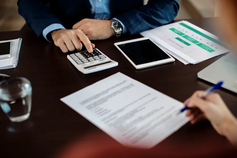 closeup real estate agent using calculator while his client is signing contract 2